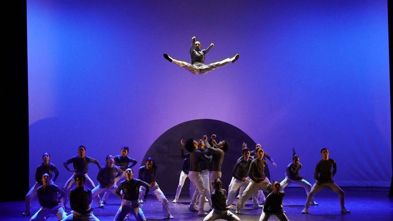 Bailarino saltando sobre o grupo de dança no palco